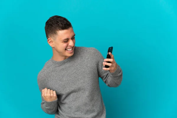 Joven Hombre Caucásico Aislado Sobre Fondo Azul Usando Teléfono Móvil —  Fotos de Stock