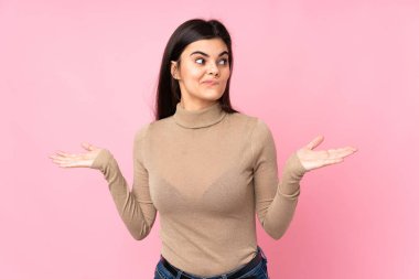 Soyutlanmış pembe arka planı olan genç bir kadın ellerini kaldırırken şüpheye düşüyor.