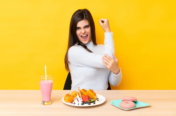 Jonge Vrouw Eten Wafels Milkshake Een Tabel Geïsoleerde Gele Achtergrond — Stockfoto