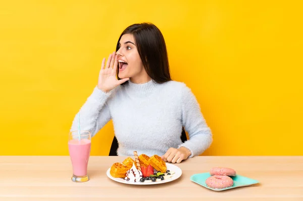 Mujer Joven Comiendo Gofres Batido Una Mesa Sobre Fondo Amarillo —  Fotos de Stock