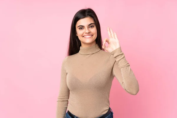 年轻女子在孤立的粉红背景上用手指显示出好的体征 — 图库照片