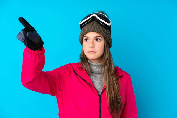青少年滑雪者女孩 戴着雪板眼镜 蓝色孤立的背景 触摸透明的屏幕 — 图库照片