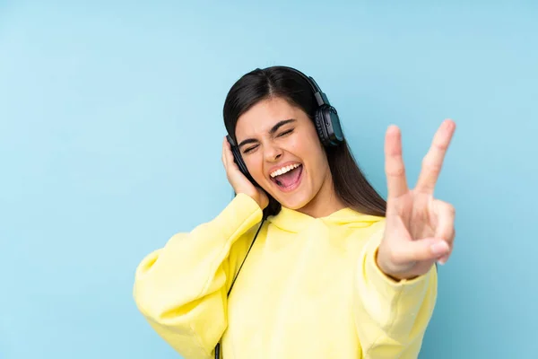 Mujer Joven Sobre Fondo Azul Aislado Escuchando Música Cantando —  Fotos de Stock