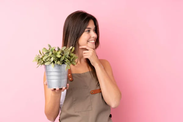 Tiener Tuinman Meisje Houden Een Plant Geïsoleerde Roze Achtergrond Denken — Stockfoto