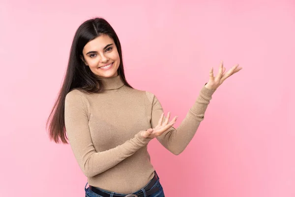 Jovem Mulher Sobre Fundo Rosa Isolado Estendendo Mãos Para Lado — Fotografia de Stock