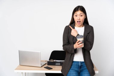 İş yerindeki Asyalı kadın beyaz arka planda izole edilmiş, şaşırmış ve işaret ediyor.