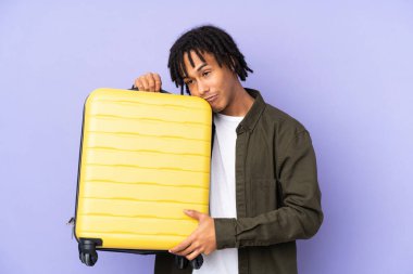 Genç Afro-Amerikan bir adam mor arka planda izole edilmiş seyahat çantası ve mutsuz