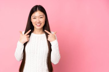 Asyalı genç bir kadın tecrit edilmiş geçmişinden dolayı baş parmak işareti yapıyor.