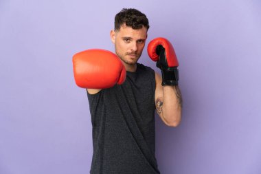 Mor arka planda boks eldivenli, beyaz, yakışıklı genç bir adam.