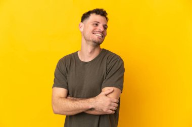 Sarı arka planda izole edilmiş, kolları bağlı ve mutlu, beyaz, yakışıklı genç bir adam.