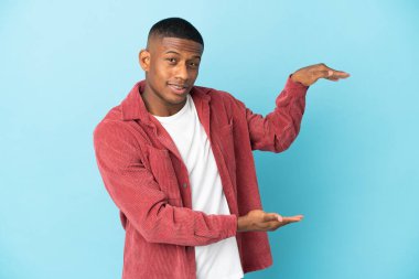 Genç latin adam mavi arka planda izole edilmiş bir ilan eklemek için kopyalama alanı tutuyor