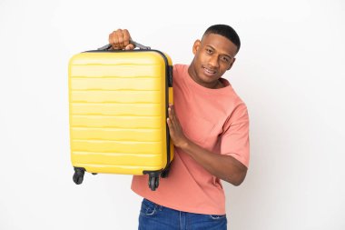 Beyaz arka planda izole edilmiş, seyahat valiziyle gezen genç Latin bir adam.
