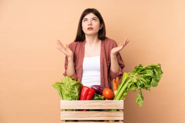 Sebzeleri yeni toplamış genç çiftçi kız kötü bir durum yüzünden hayal kırıklığına uğramış bir kutuda.