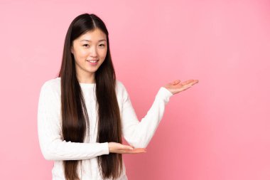 Asyalı genç bir kadın soyutlanmış arka planda. Davet edilmek için ellerini yana uzatıyor.