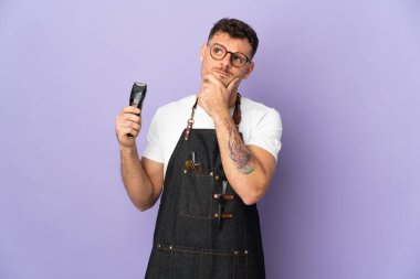 Önlüklü beyaz bir adam mor arka planda kuşkuları var.