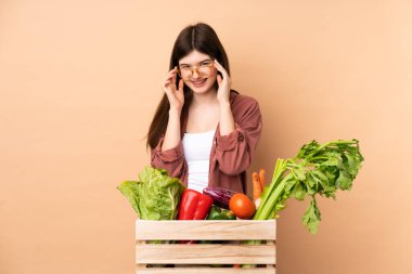 Gözlüklü bir kutuda taze sebze toplayan genç çiftçi kız şaşırdı.