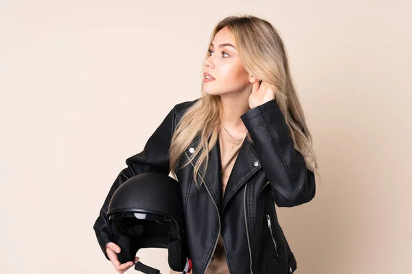 오토바이 헬멧을 러시아 소녀는 베이지 배경에서 무언가를 — 스톡 사진