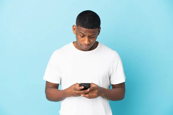 Jovem Latino Isolado Fundo Azul Usando Telefone Celular — Fotografia de Stock