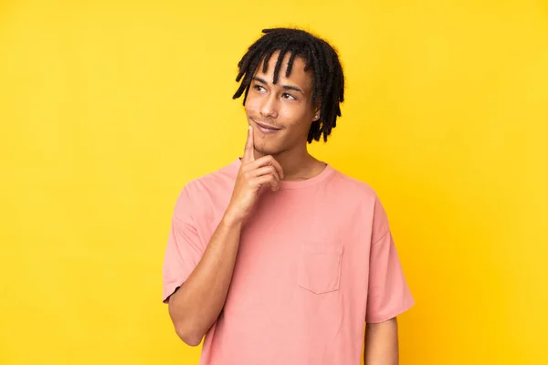 Νεαρός Αφροαμερικάνος Απομονωμένος Κίτρινο Φόντο Σκέφτεται Μια Ιδέα Ενώ Κοιτάζει — Φωτογραφία Αρχείου