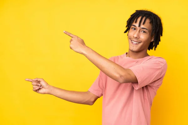 年轻的非洲裔美国人在黄色背景下被隔离 手指指向侧面并展示了一种产品 — 图库照片