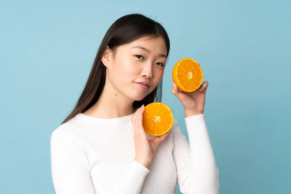 Νεαρή Ασιάτισσα Που Κρατάει Ένα Πορτοκάλι Πάνω Από Απομονωμένο Μπλε — Φωτογραφία Αρχείου