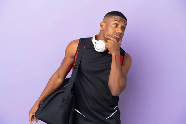 年轻的运动拉丁男子与体育袋隔离紫色背景有疑问 — 图库照片