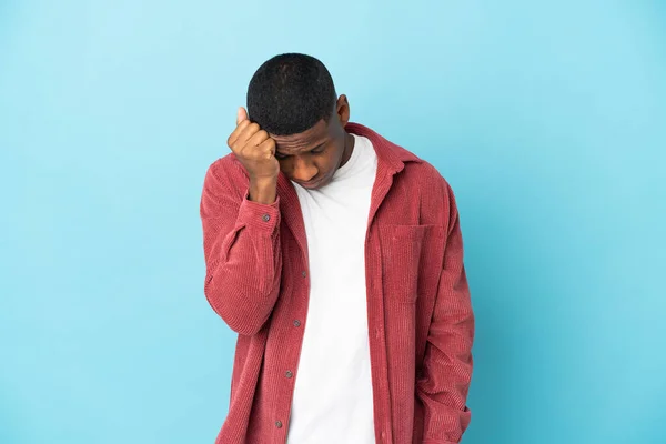 Young latin man isolated on blue background with headache