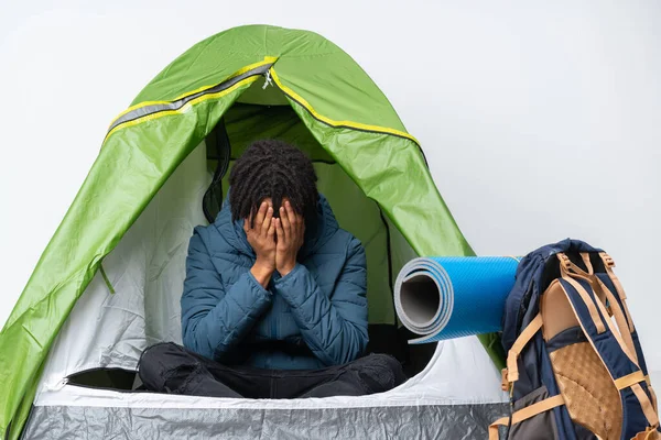 Young african american man inside a camping green tent with tired and sick expression
