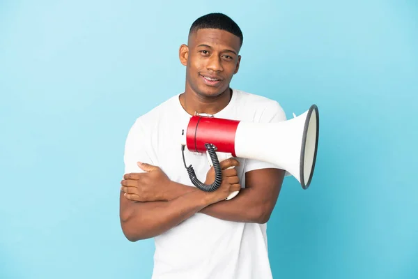 Jovem Latino Isolado Fundo Azul Segurando Megafone Sorrindo — Fotografia de Stock