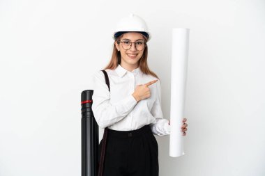 Miğferli ve elinde beyaz arka planda izole edilmiş planları olan genç bir mimar kadın bir ürünü sunmak için kenarı işaret ediyor.