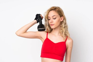 Beyaz arka planda izole edilmiş genç sarışın kadın ağırlık kaldırıyor.