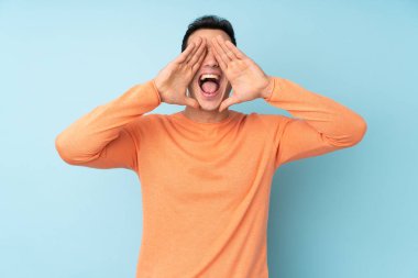 Beyaz tenli yakışıklı adam mavi arka planda izole edilmiş bağırıyor ve bir şeyler söylüyor.