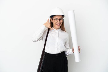 Miğferli ve elinde beyaz arka planda izole edilmiş planları olan genç bir mimar kadın telefon jesti yapıyor. Bana geri dönüş işareti ver.