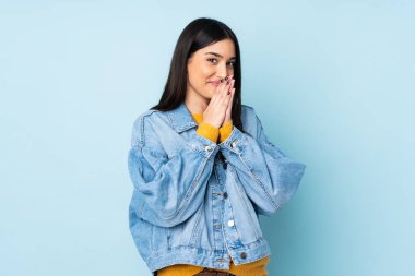 Mavi arka planda izole edilmiş genç beyaz kadın avuç içlerini bir arada tutuyor. İnsan bir şey ister.