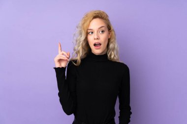 Mor arka planda izole edilmiş genç sarışın bir kadın bir fikrin parmağı yukarı kaldırdığını düşünüyor.