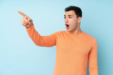 Kafkasyalı yakışıklı genç adam mavi arka planda izole edilmiş.