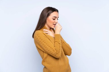 Mavi arka planda izole edilmiş genç beyaz kadın öksürükten muzdarip ve kötü hissediyor.