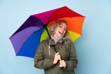 Mavi arka planda şemsiye tutan kadın