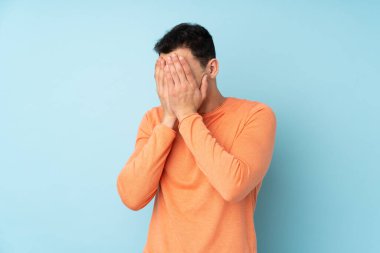 Kafkasyalı yakışıklı genç adam mavi arka planda izole edilmiş, yorgun ve hasta bir ifadeyle.