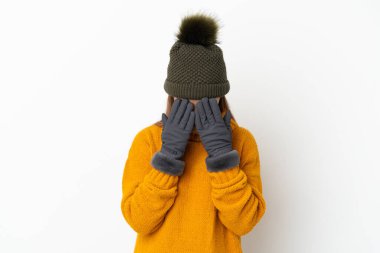 Kışlık şapkalı genç kız yorgun ve hasta bir ifadeyle beyaz arka planda izole edilmiş.