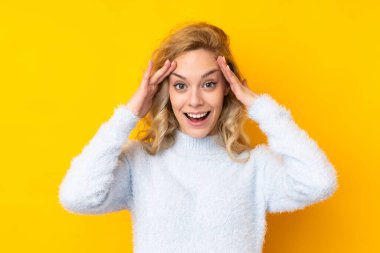 Sarı arka planda izole edilmiş genç sarışın kadın. Sürpriz bir ifadeyle.