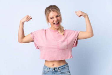 Sarışın kadın izole edilmiş mavi arka planda güçlü hareketler yapıyor.