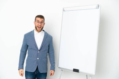 Beyaz zemin üzerinde sunum yapan genç iş kadını sürpriz bir yüz ifadesiyle beyaz arka planda izole edildi