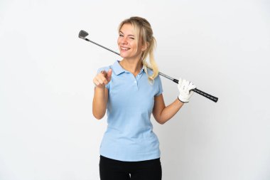 Beyaz arka planda izole edilmiş genç Rus golfçü kadın mutlu bir ifadeyle ön tarafı işaret ediyor.