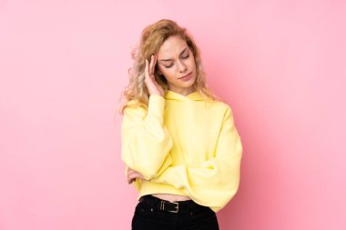 Pembe arka planda izole edilmiş, başağrısı olan, eşofman üstü giyen genç sarışın kadın.
