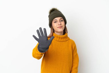 Beyaz arka planda izole edilmiş, kış şapkalı genç kız parmaklarıyla beşi sayıyor.