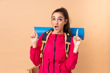 Büyük bir sırt çantalı genç dağcı kız bej arka planda izole edilmiş işaret parmağıyla işaret etmek harika bir fikir.