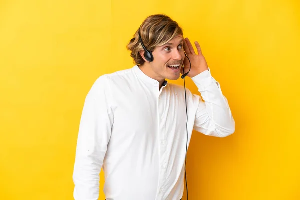 Telemarketer Pracuje Słuchawkami Odizolowanymi Żółtym Tle Słuchając Czegoś Kładąc Rękę — Zdjęcie stockowe