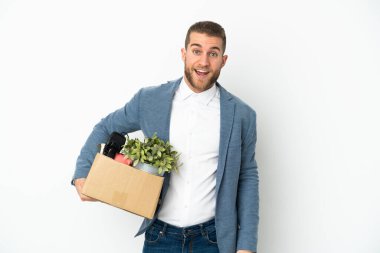 Beyaz arka planda izole edilmiş, sürpriz bir yüz ifadesi olan şeylerle dolu bir kutuyu alırken genç beyaz tenli hamle yapıyor.