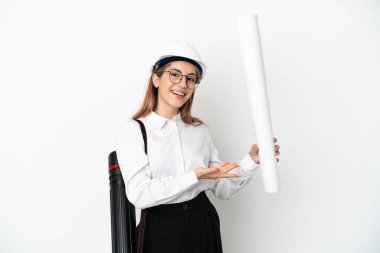 Miğferli ve elinde planları olan genç bir mimar. Beyaz arka planda izole edilmiş. Davet edilmek için ellerini yana uzatıyor.